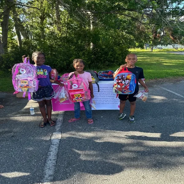 Children with school supply backpacks at community event